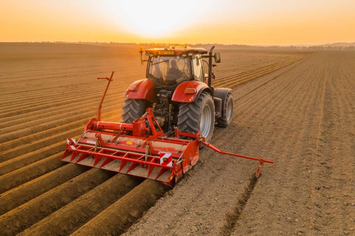 Tractor harrows in field dragging plow on purified soil