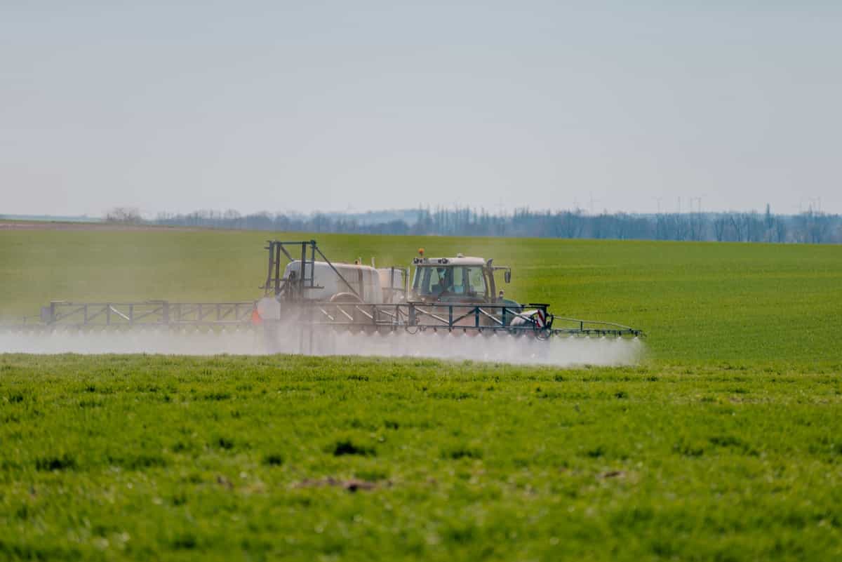 Spraying Herbicides in the field using tractor with spray attachment